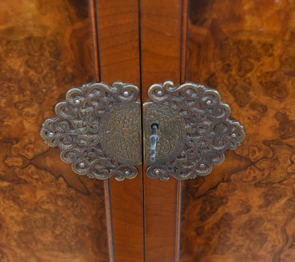 An Art Deco burr walnut drinks cabinet on a carved cabriole leg stand with ornate brass hardware and two lower drawers. View VI