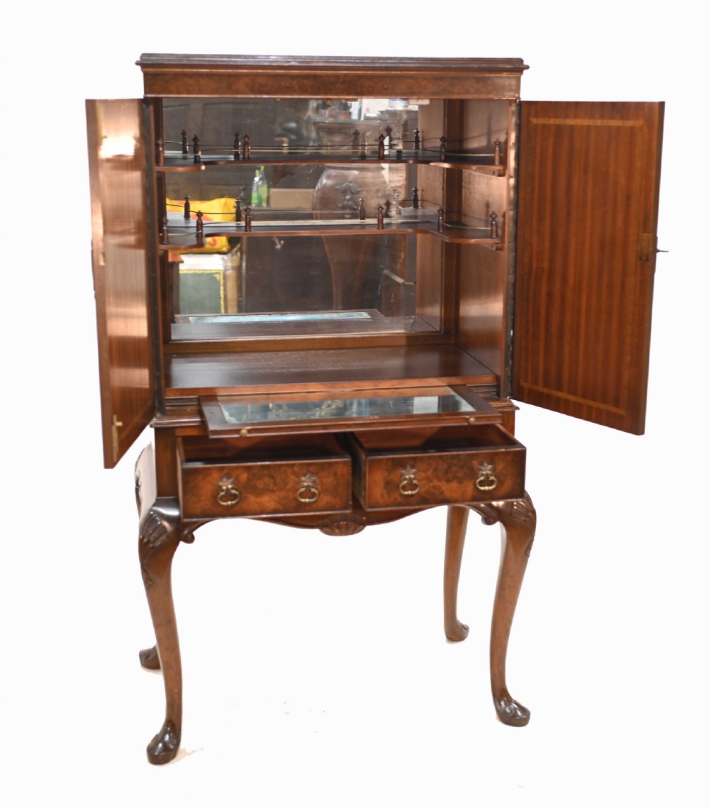 An Art Deco burr walnut drinks cabinet on a carved cabriole leg stand with ornate brass hardware and two lower drawers. View VII