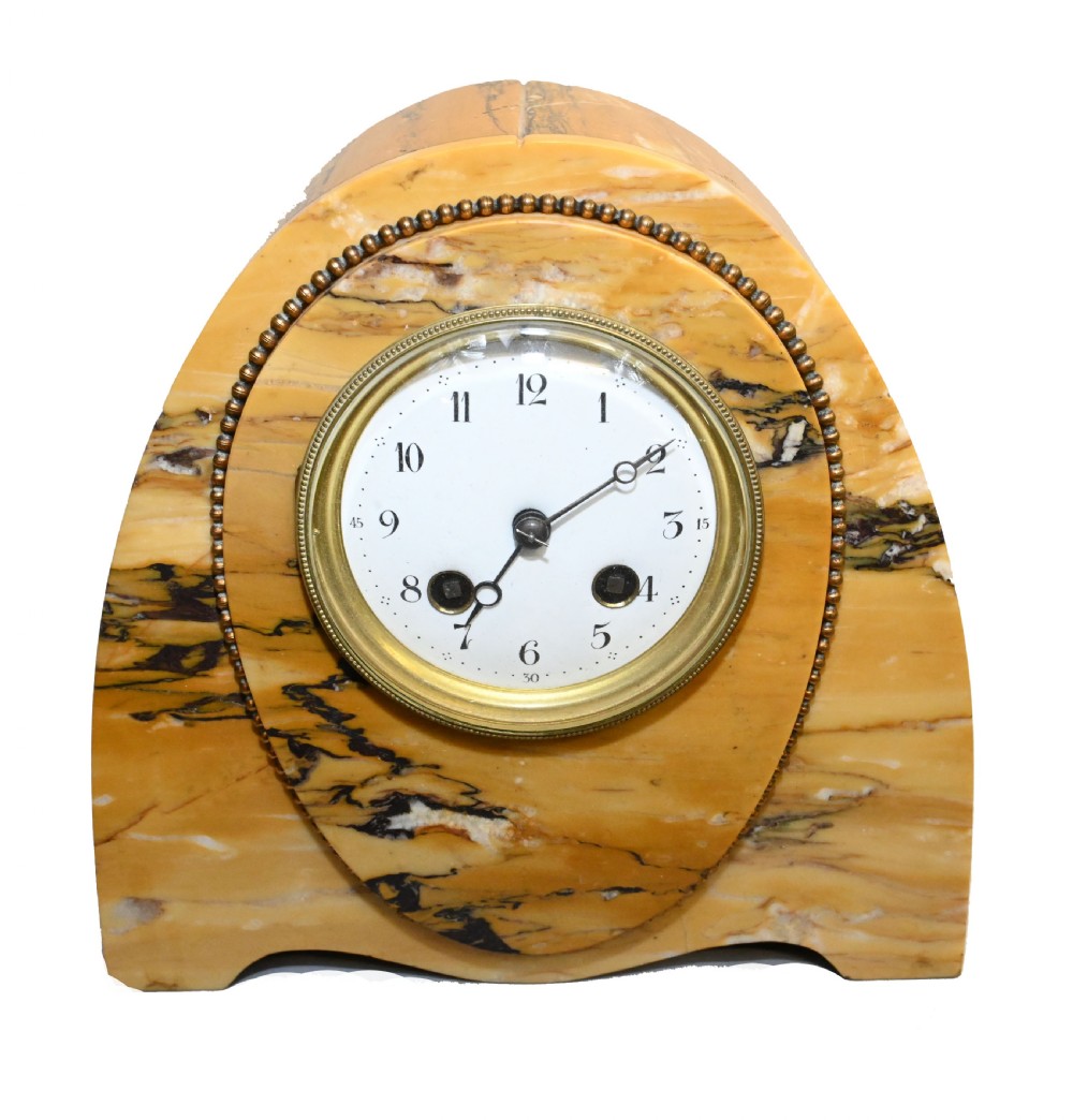 An antique French three-piece garniture set featuring an arched yellow veined marble clock flanked by two matching marble pedestal tazzas. View II