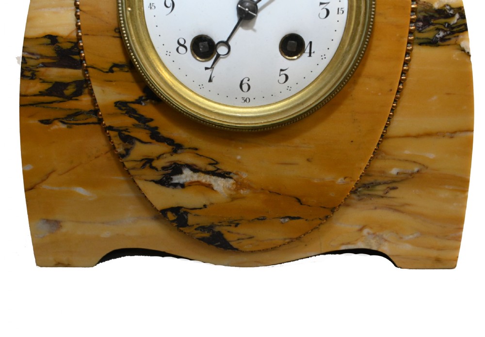 An antique French three-piece garniture set featuring an arched yellow veined marble clock flanked by two matching marble pedestal tazzas. View III
