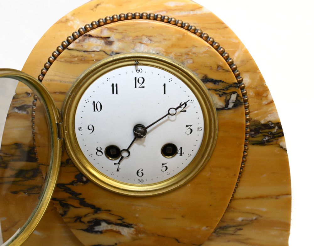 An antique French three-piece garniture set featuring an arched yellow veined marble clock flanked by two matching marble pedestal tazzas. View IV