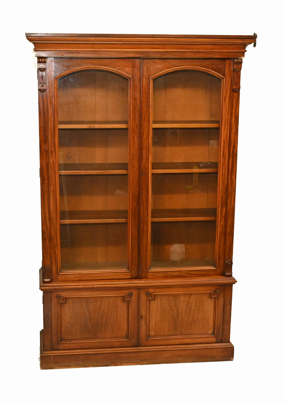 A Victorian mahogany library bookcase featuring two upper arched glazed doors with shelves set above a lower cupboard base.