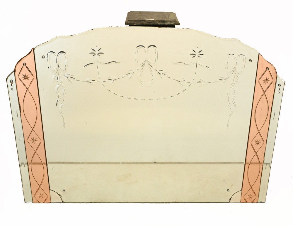 An Art Deco frameless overmantel mirror featuring central etched garland detailing flanked by peach-tinted glass side panels with star engravings.