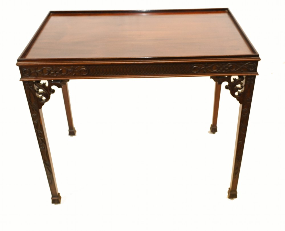 A Chippendale style mahogany silver table featuring a raised gallery top edge, carved blind-fret frieze, pierced corner brackets, and square section carved legs.