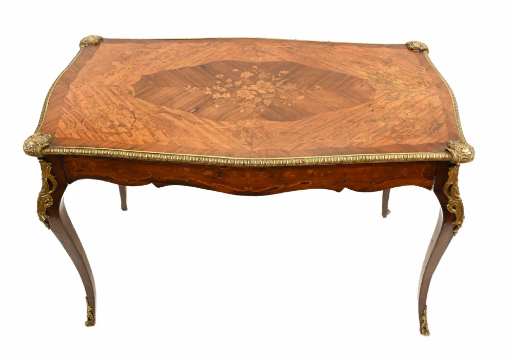 A French style writing table featuring floral marquetry wood veneers, cabriole legs, and ornate gilt-bronze mounts. View II