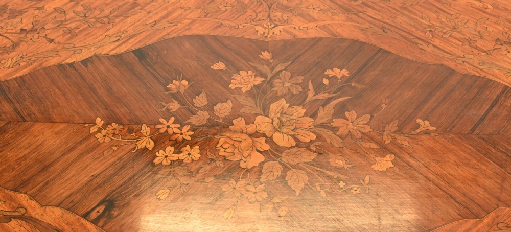 A French style writing table featuring floral marquetry wood veneers, cabriole legs, and ornate gilt-bronze mounts. View III
