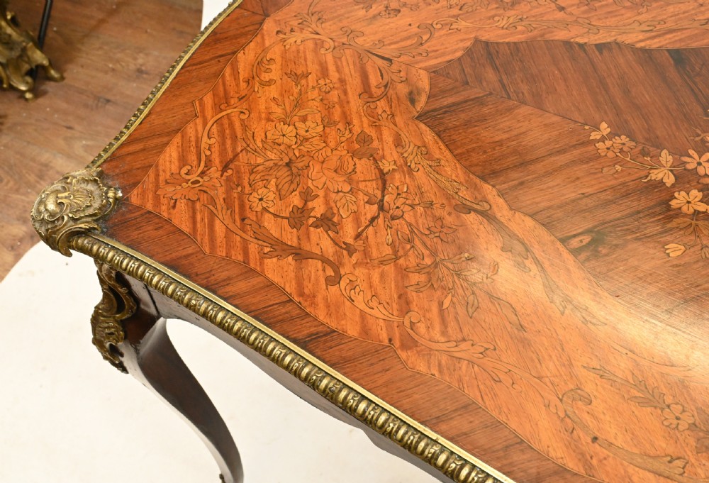 A French style writing table featuring floral marquetry wood veneers, cabriole legs, and ornate gilt-bronze mounts. View IV