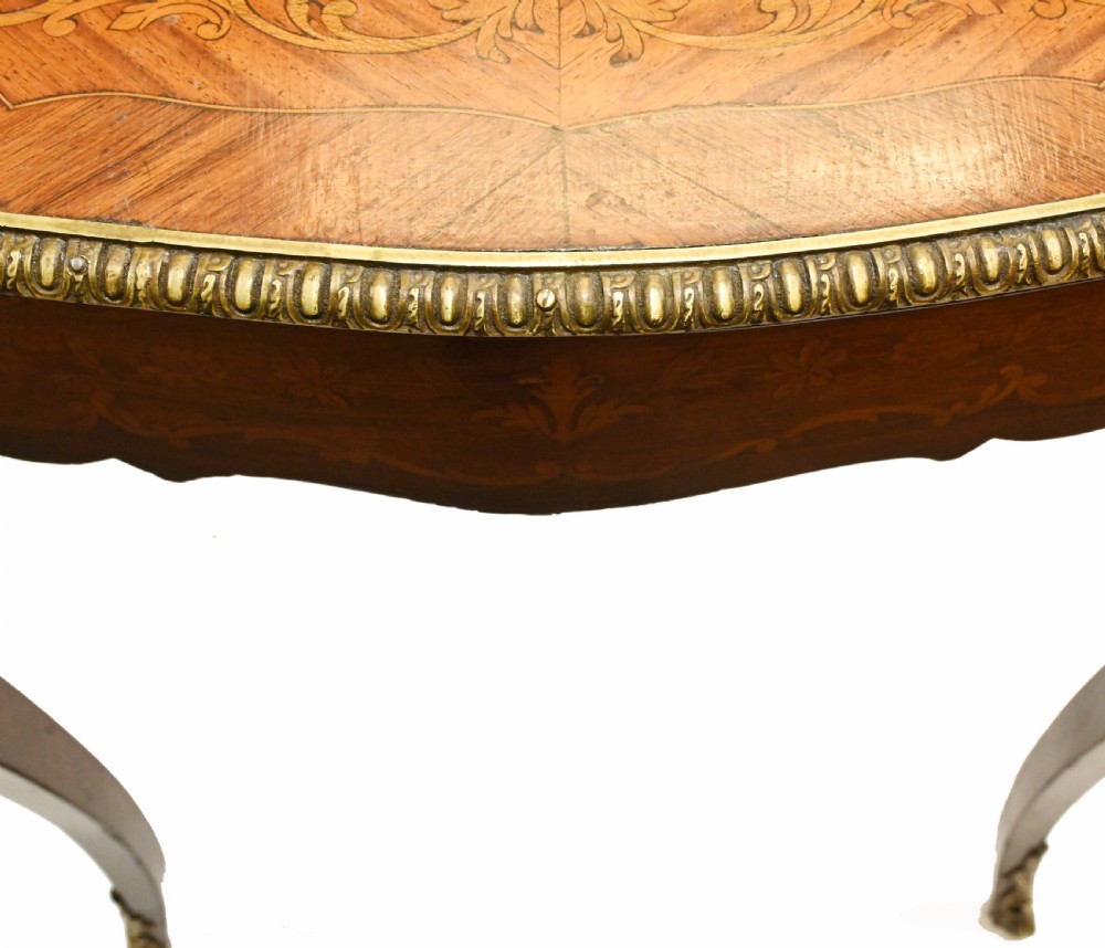 A French style writing table featuring floral marquetry wood veneers, cabriole legs, and ornate gilt-bronze mounts. View X
