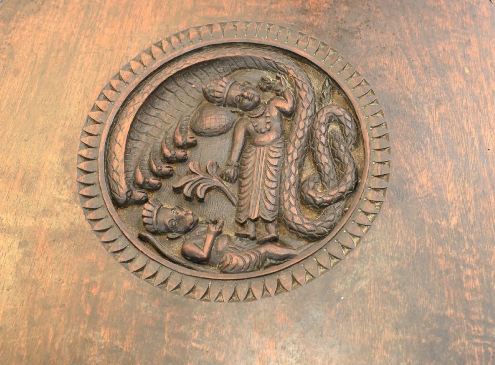 A circular dark carved teak side table featuring dense floral relief carving on the top and apron supported by a tripod base. View XI