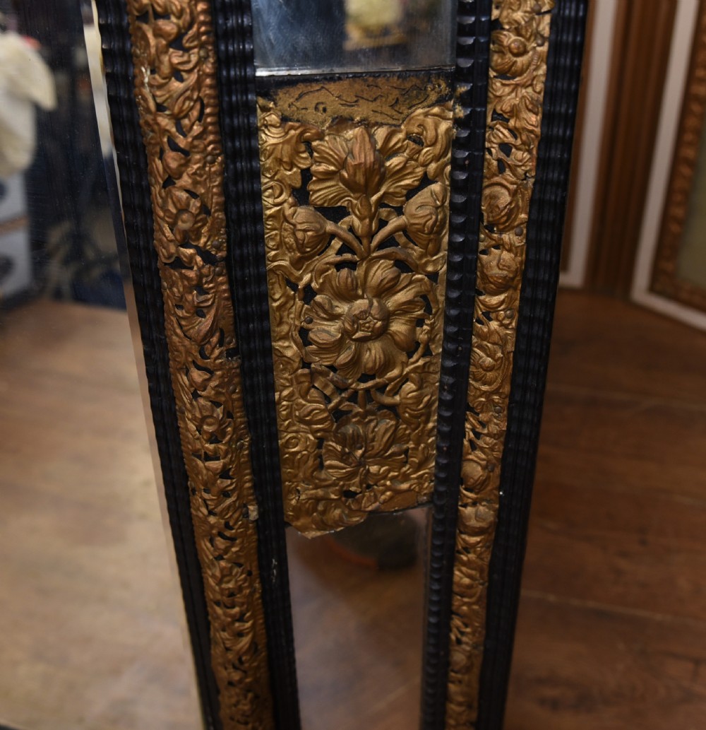 An antique French cushion mirror featuring an ornate repousse brass crest, detailed floral metal mounts, and a multi-panelled glass frame. View VIII