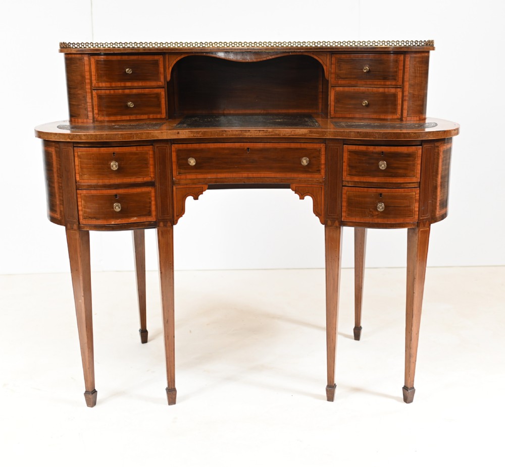 An Edwardian mahogany kidney-shaped writing desk featuring a brass gallery top, inlaid drawers, black leather writing inserts, and tapered legs. View III