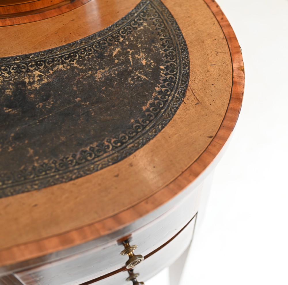 An Edwardian mahogany kidney-shaped writing desk featuring a brass gallery top, inlaid drawers, black leather writing inserts, and tapered legs. View VIII