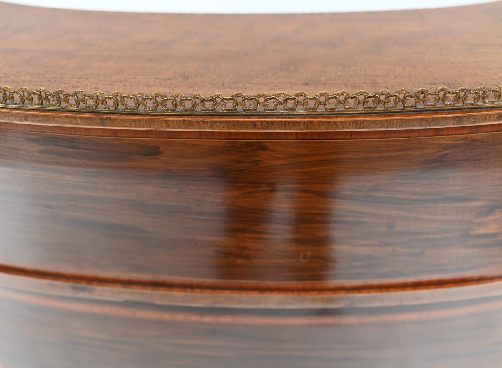An Edwardian mahogany kidney-shaped writing desk featuring a brass gallery top, inlaid drawers, black leather writing inserts, and tapered legs. View XVI