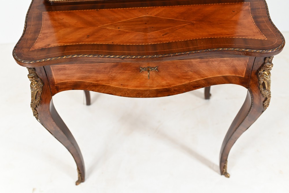 A French Louis XV style kingwood bonheur de jour desk featuring two upper cabinet doors inset with oval painted porcelain plaques, ornate metal mounts, and cabriole legs. View V