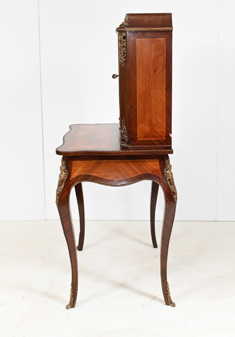 A French Louis XV style kingwood bonheur de jour desk featuring two upper cabinet doors inset with oval painted porcelain plaques, ornate metal mounts, and cabriole legs. View VIII
