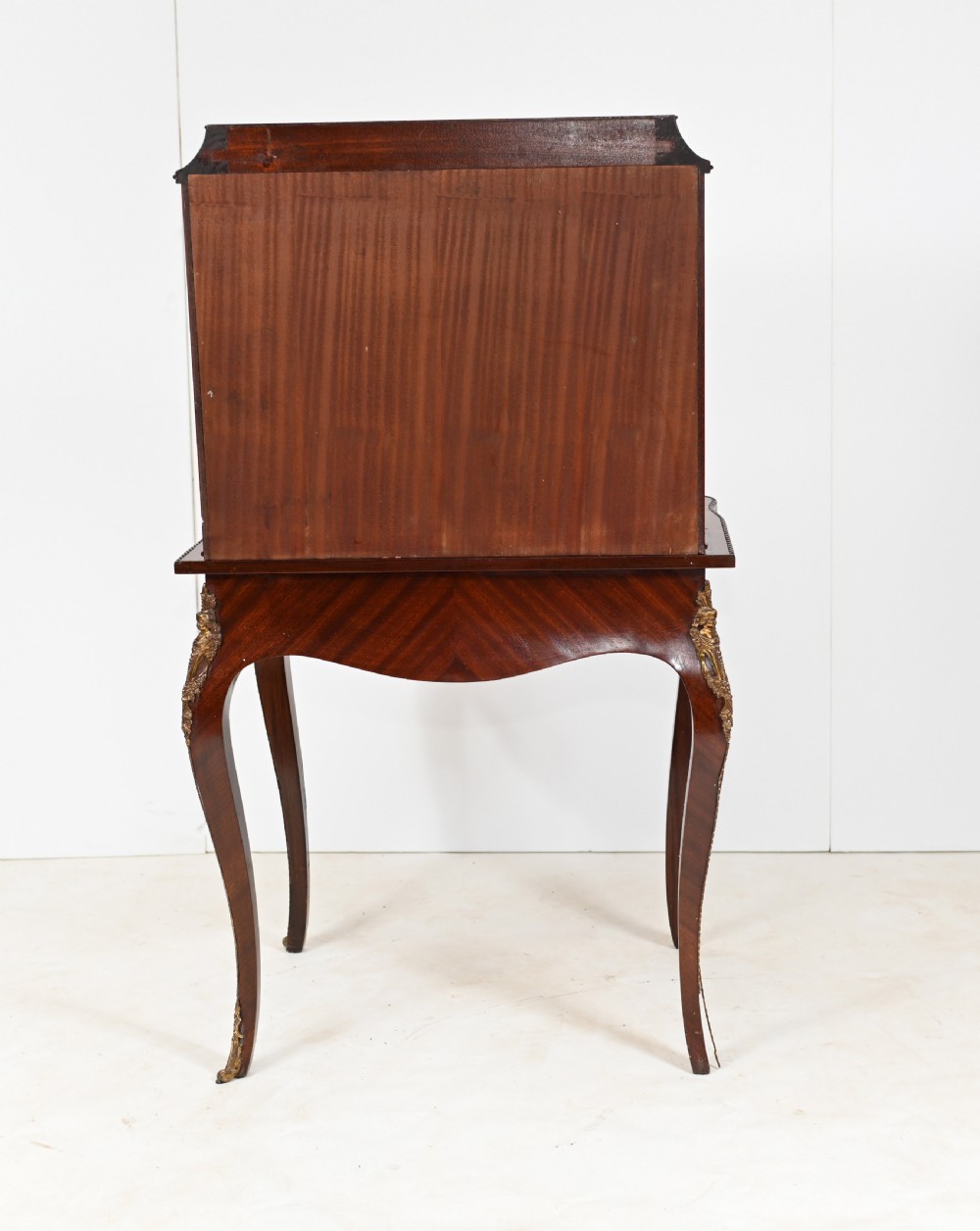 A French Louis XV style kingwood bonheur de jour desk featuring two upper cabinet doors inset with oval painted porcelain plaques, ornate metal mounts, and cabriole legs. View X