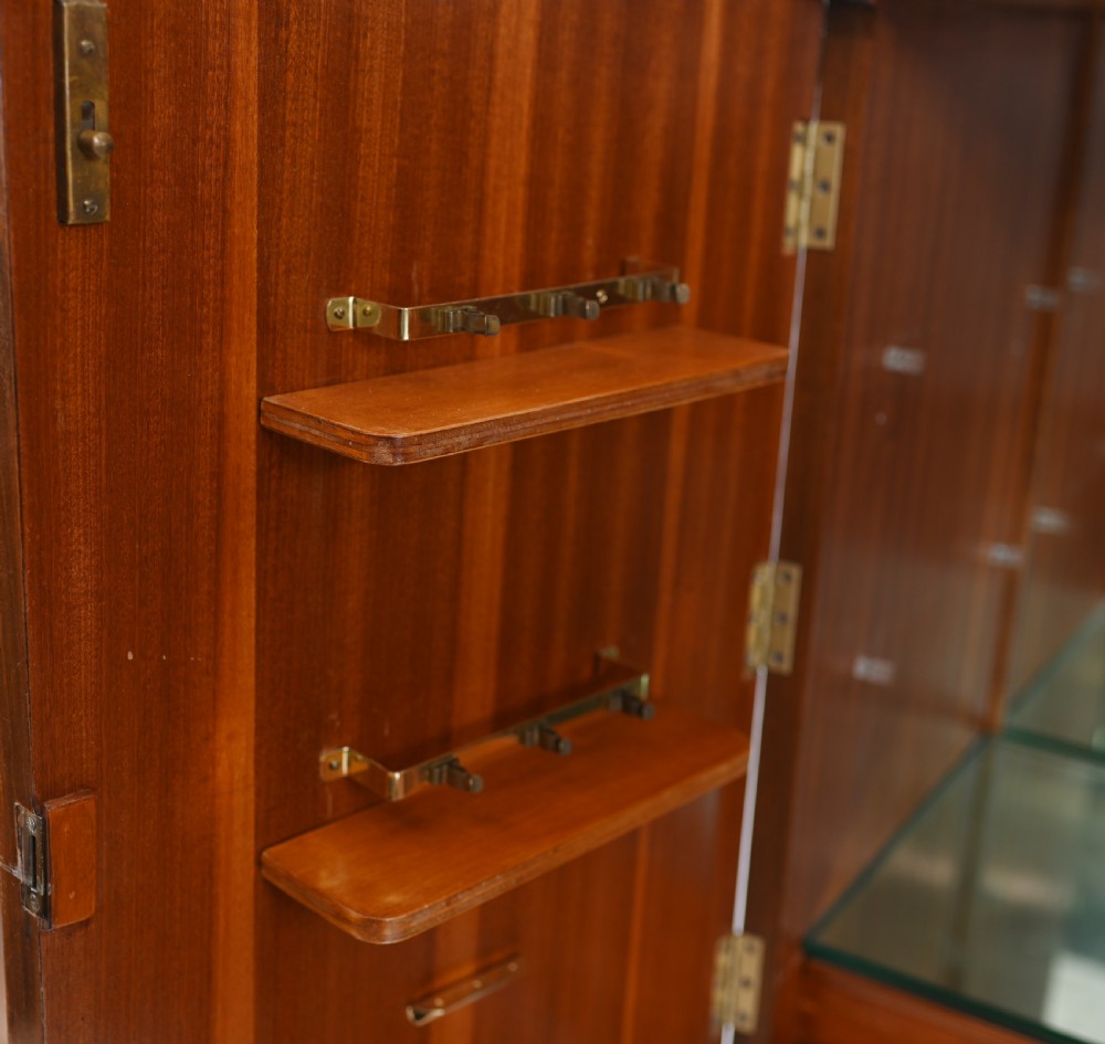 A two-tier Art Deco burr walnut cocktail cabinet featuring decorative brass strap hinges, lock plates, carved cresting, and cabriole legs. View VII