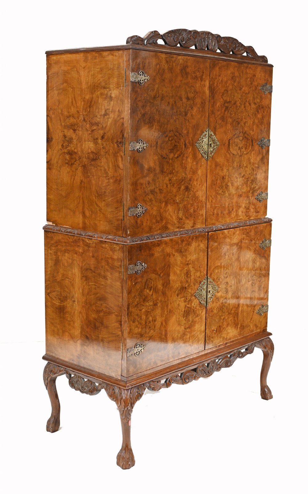 A two-tier Art Deco burr walnut cocktail cabinet featuring decorative brass strap hinges, lock plates, carved cresting, and cabriole legs. View IX