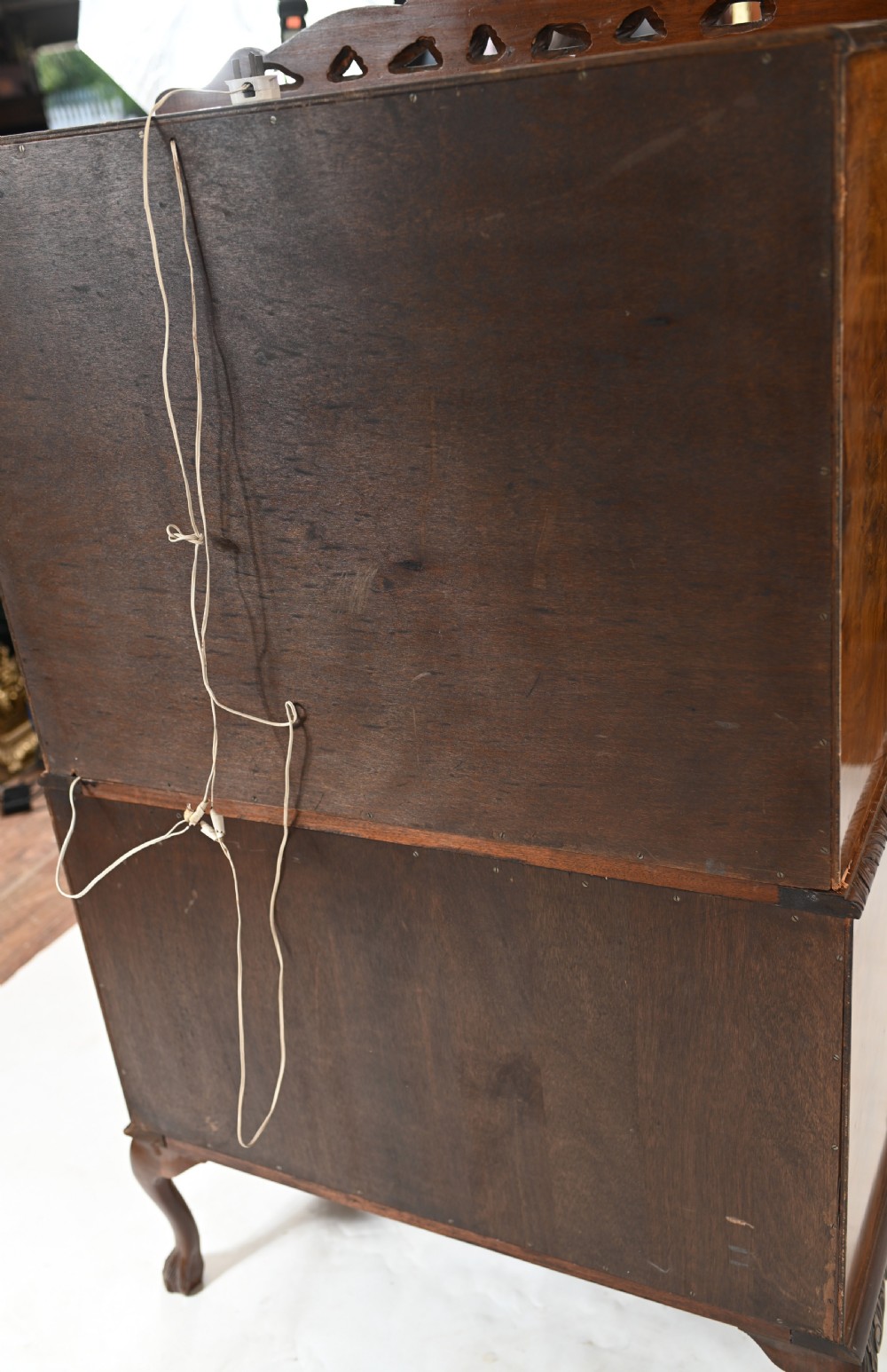 A two-tier Art Deco burr walnut cocktail cabinet featuring decorative brass strap hinges, lock plates, carved cresting, and cabriole legs. View XII