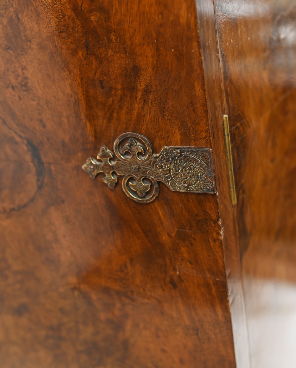 A two-tier Art Deco burr walnut cocktail cabinet featuring decorative brass strap hinges, lock plates, carved cresting, and cabriole legs. View XIII