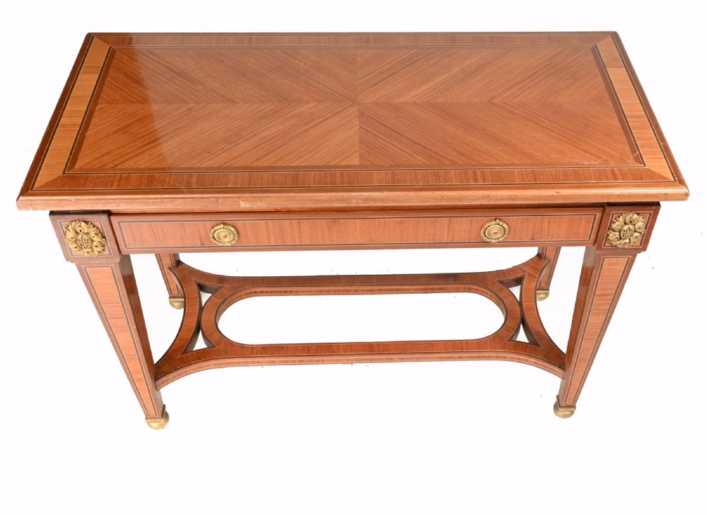 A pair of French Empire style mahogany console tables featuring satinwood crossbanding, gilt-bronze rosette mounts, and curved lower stretchers. View VI