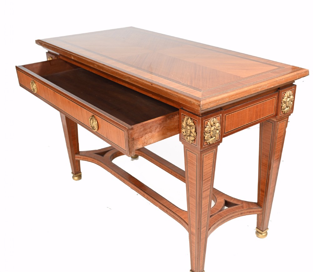 A pair of French Empire style mahogany console tables featuring satinwood crossbanding, gilt-bronze rosette mounts, and curved lower stretchers. View VIII