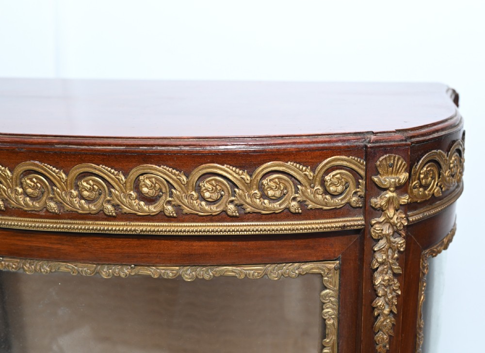 A French Vernis Martin style mahogany display cabinet featuring curved glass panels, gilt-bronze mounts, and a hand-painted pastoral scene on the lower door. View IV
