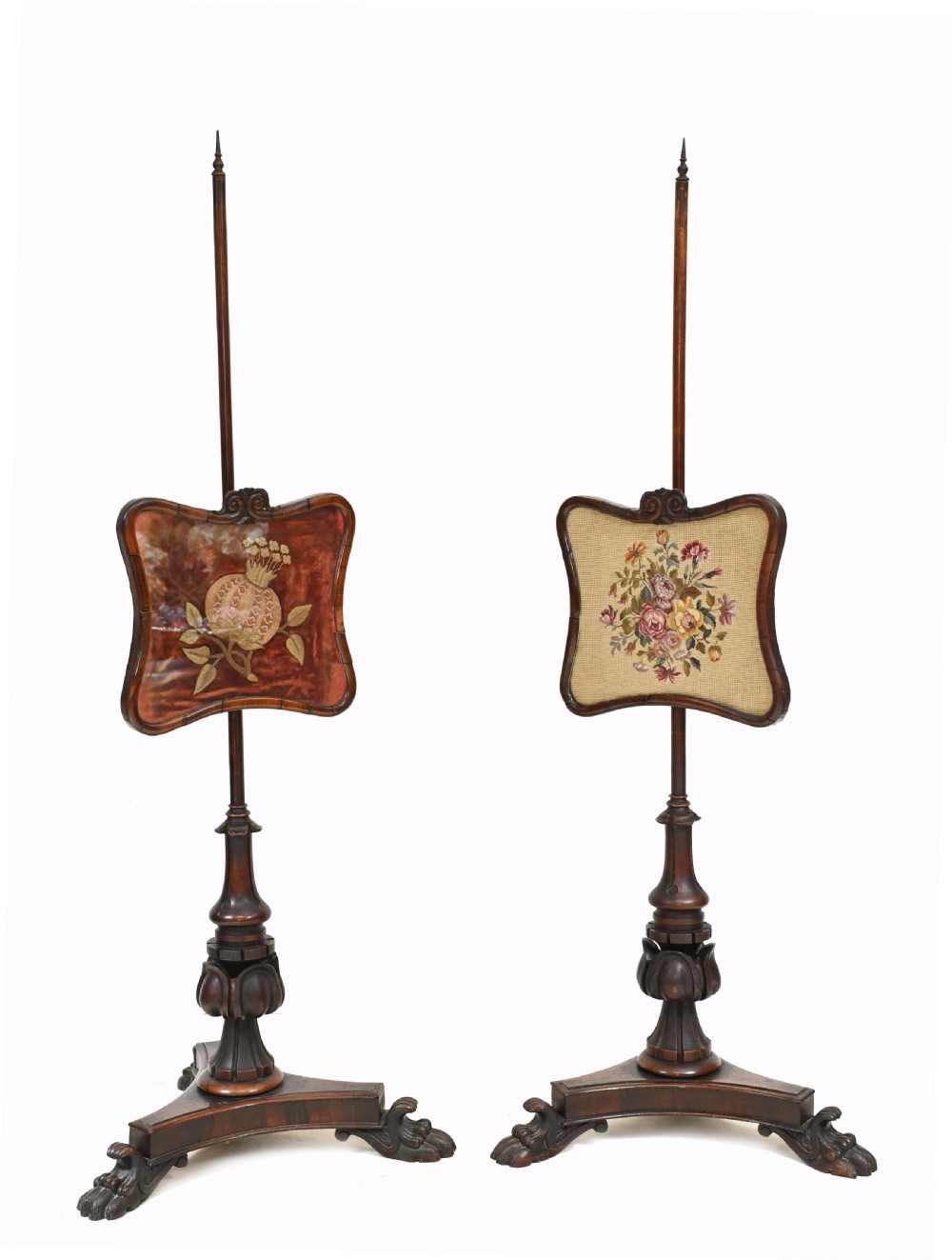 A pair of antique Regency rosewood pole screens with carved triform bases and adjustable framed needlepoint tapestry panels.
