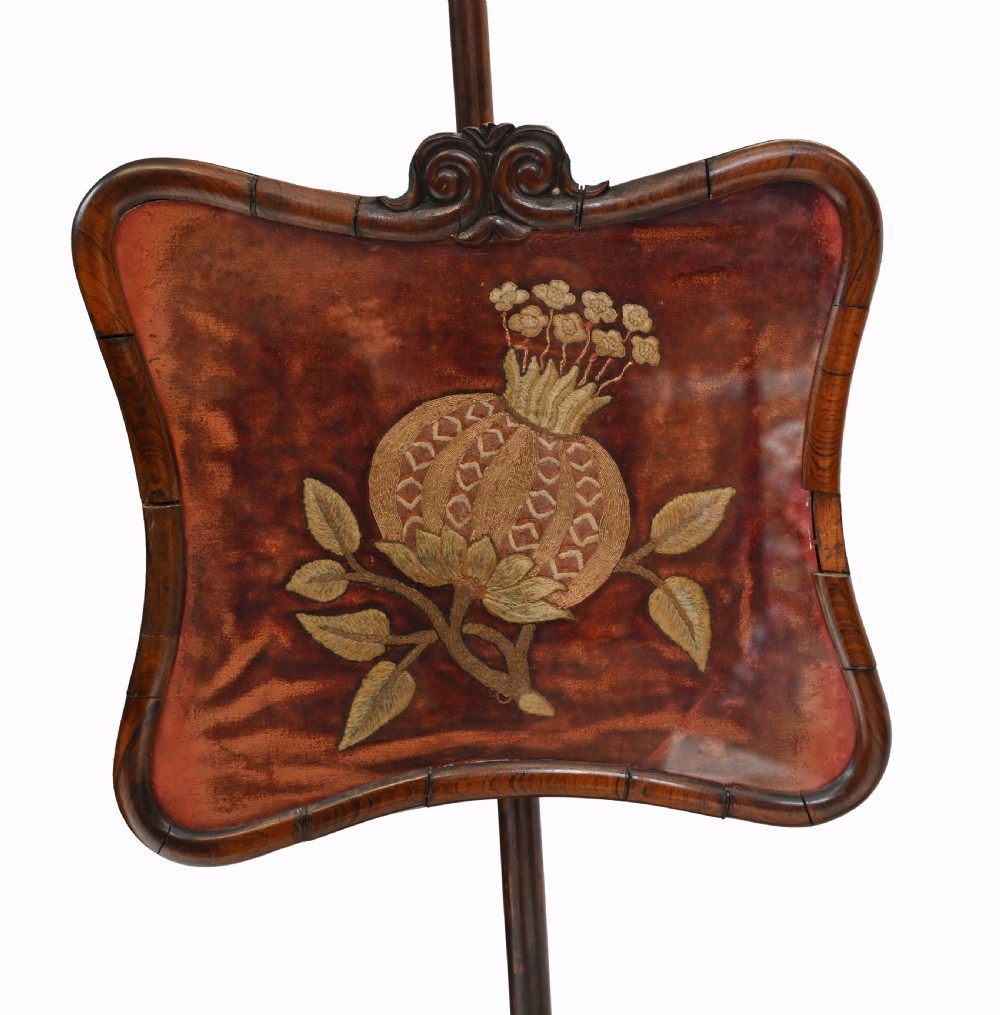 A pair of antique Regency rosewood pole screens with carved triform bases and adjustable framed needlepoint tapestry panels. View II