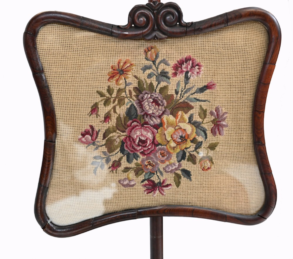 A pair of antique Regency rosewood pole screens with carved triform bases and adjustable framed needlepoint tapestry panels. View X