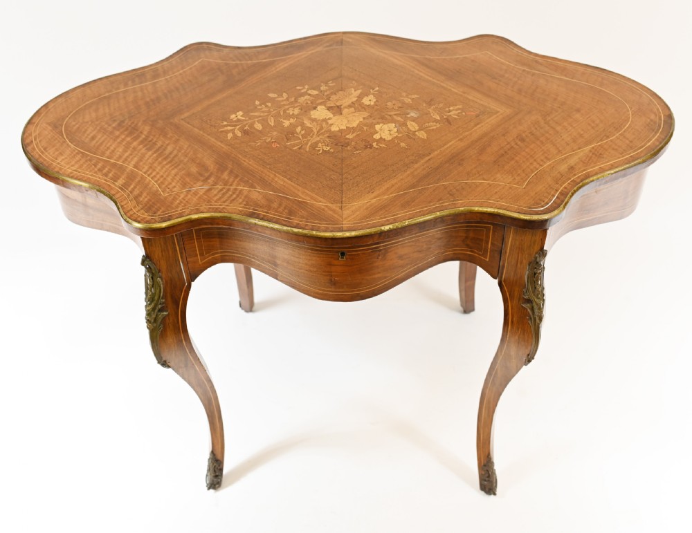 A French Louis XV style centre table featuring a serpentine top with floral marquetry inlay, slender cabriole legs, and metal mounts. View II
