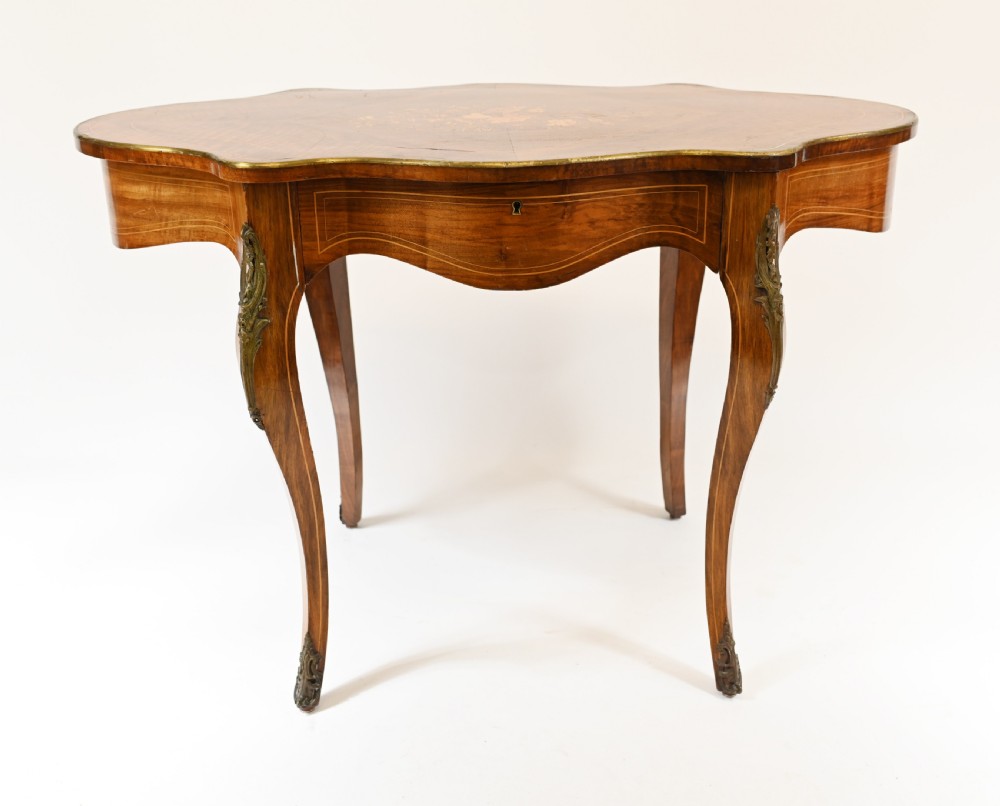 A French Louis XV style centre table featuring a serpentine top with floral marquetry inlay, slender cabriole legs, and metal mounts. View IV