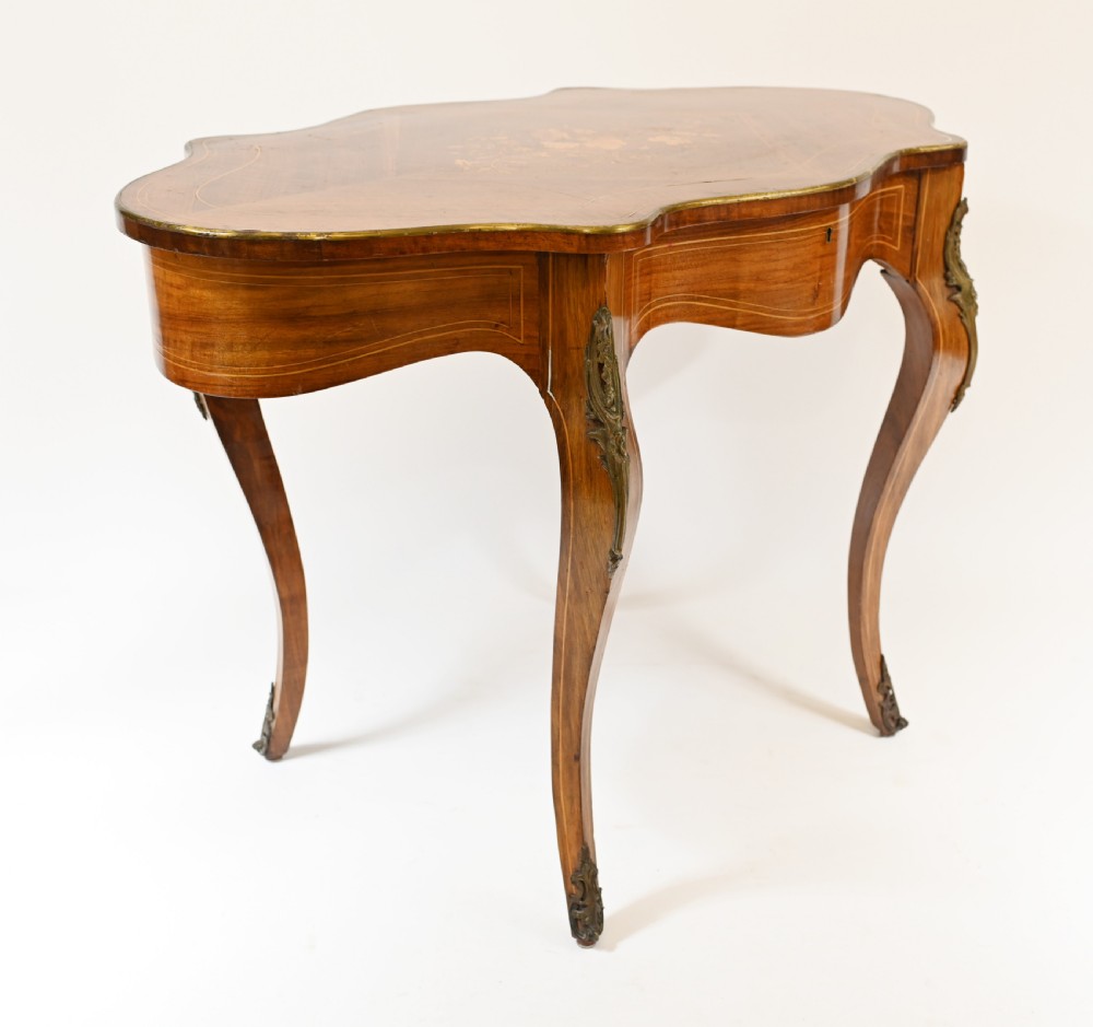 A French Louis XV style centre table featuring a serpentine top with floral marquetry inlay, slender cabriole legs, and metal mounts. View VI