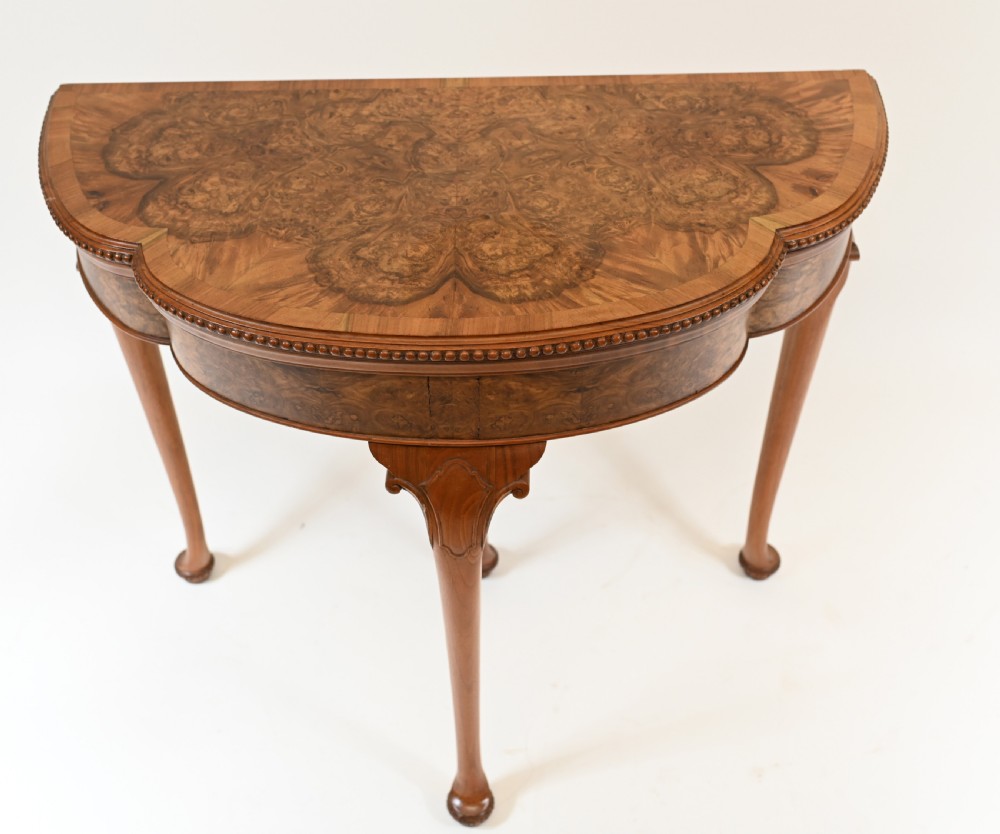 A Queen Anne style burr walnut fold-over card table featuring a scalloped demilune top, bead moulding, and four cabriole legs ending in pad feet. View II