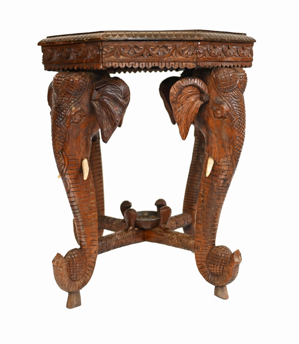 An octagonal carved wooden side table featuring three legs sculpted in the shape of elephant heads with trunks curving down to form the feet. View VII