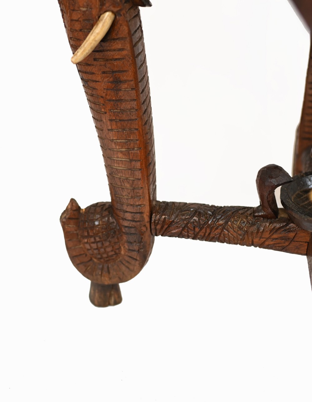An octagonal carved wooden side table featuring three legs sculpted in the shape of elephant heads with trunks curving down to form the feet. View X
