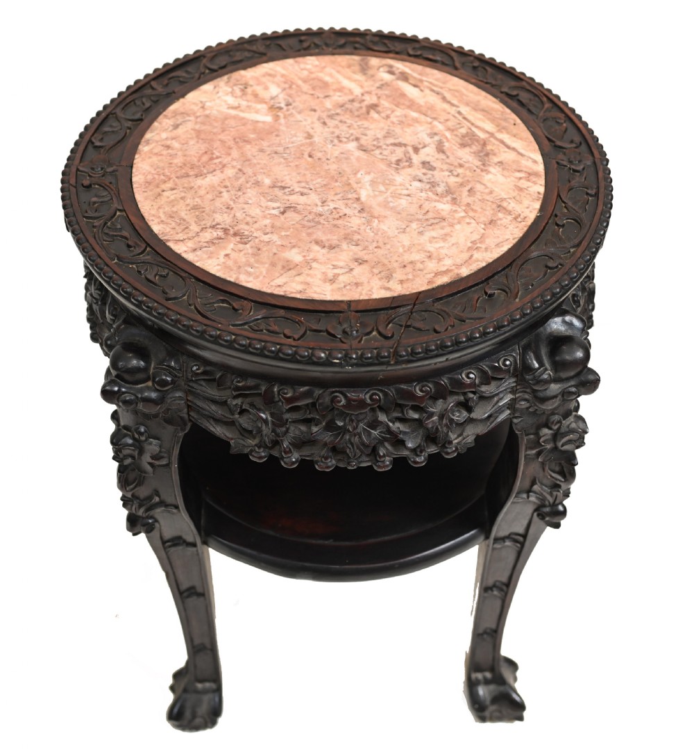 An antique Chinese dark hardwood side table featuring a circular inset marble top, openwork carved floral apron, lower tier, and carved legs. View III