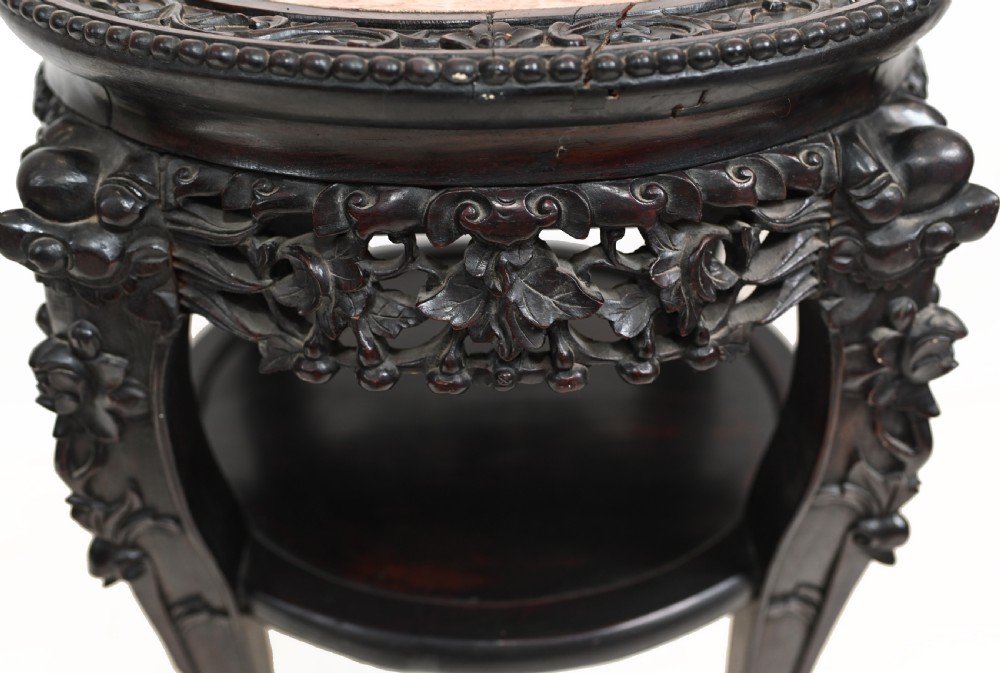 An antique Chinese dark hardwood side table featuring a circular inset marble top, openwork carved floral apron, lower tier, and carved legs. View IV