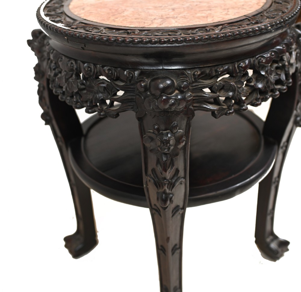 An antique Chinese dark hardwood side table featuring a circular inset marble top, openwork carved floral apron, lower tier, and carved legs. View V