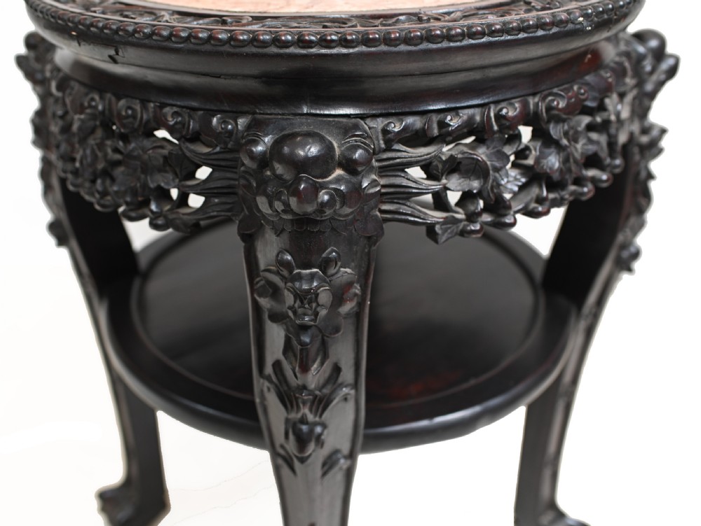 An antique Chinese dark hardwood side table featuring a circular inset marble top, openwork carved floral apron, lower tier, and carved legs. View VII