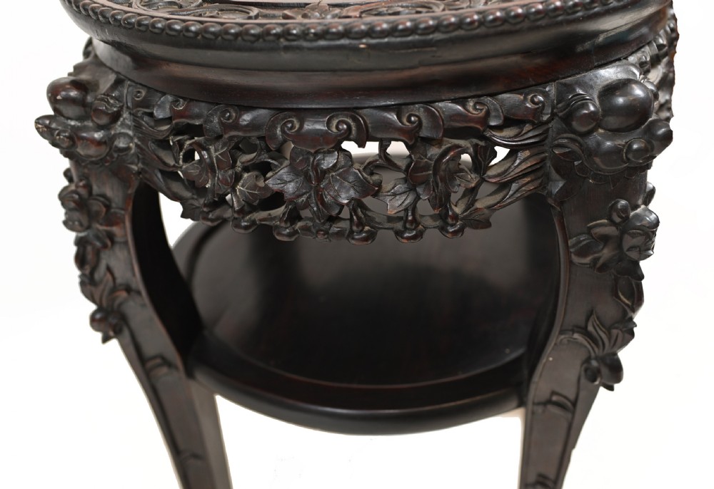 An antique Chinese dark hardwood side table featuring a circular inset marble top, openwork carved floral apron, lower tier, and carved legs. View VIII