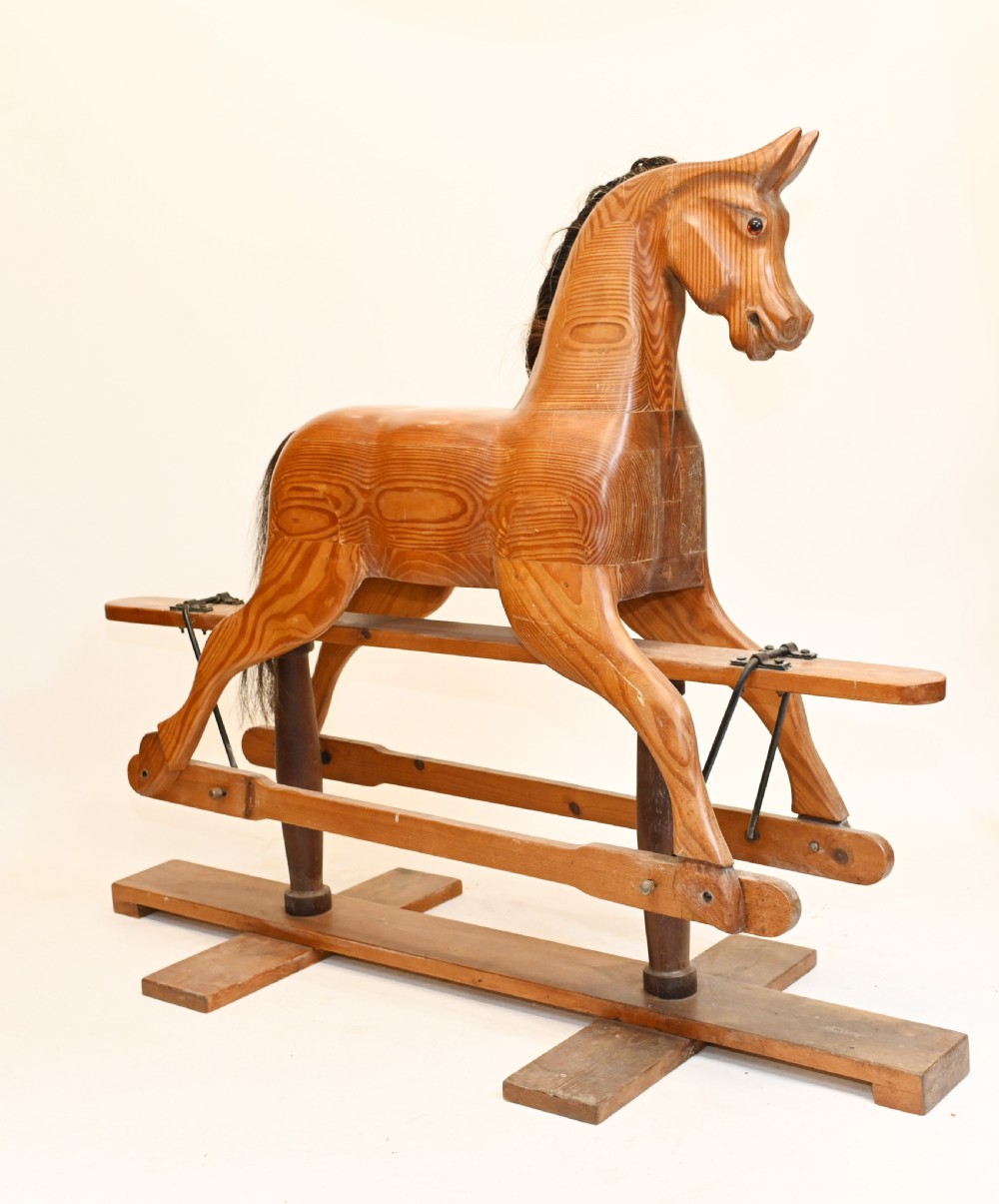A hand-carved wooden rocking horse on a stationary wooden glider stand featuring a dark horsehair mane and tail.