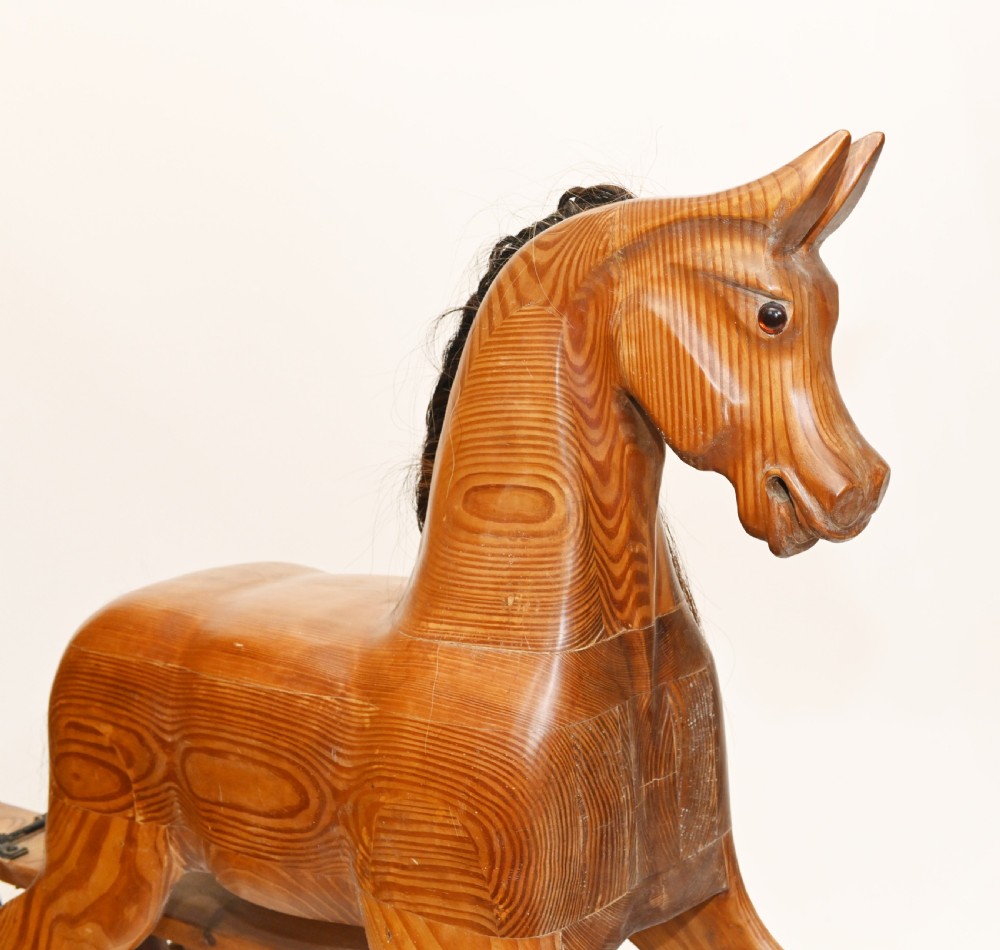 A hand-carved wooden rocking horse on a stationary wooden glider stand featuring a dark horsehair mane and tail. View II