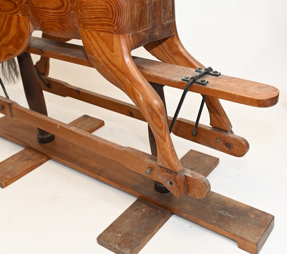 A hand-carved wooden rocking horse on a stationary wooden glider stand featuring a dark horsehair mane and tail. View III