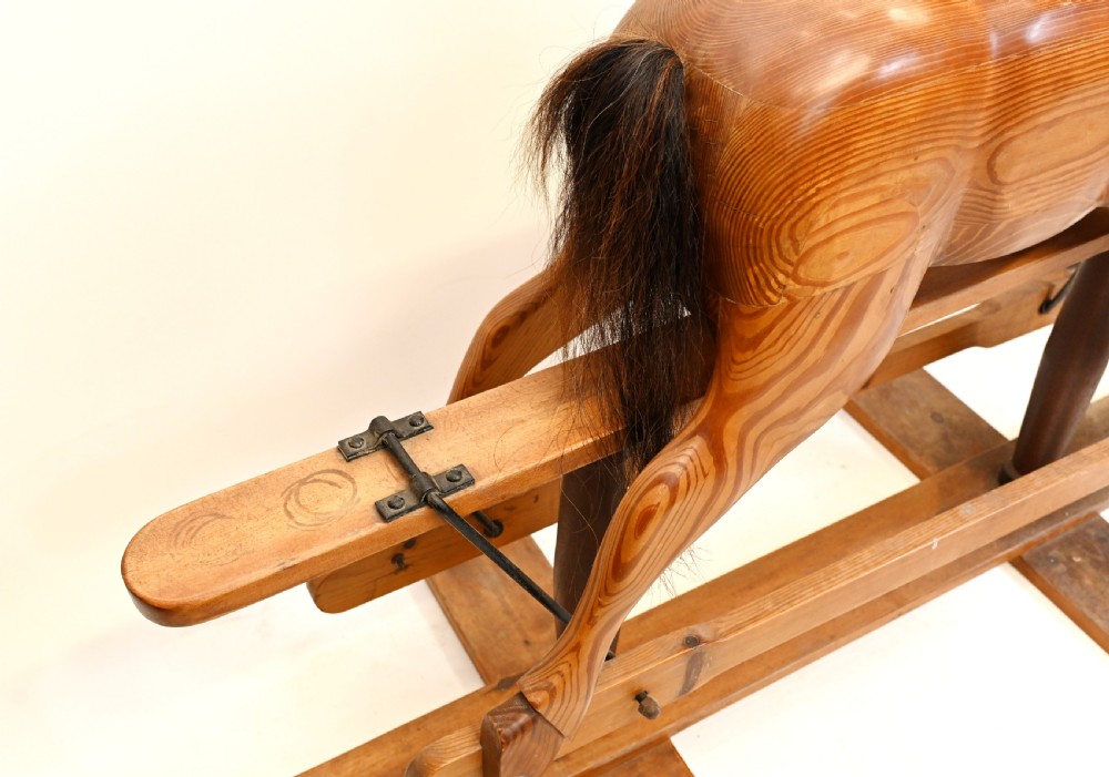 A hand-carved wooden rocking horse on a stationary wooden glider stand featuring a dark horsehair mane and tail. View V