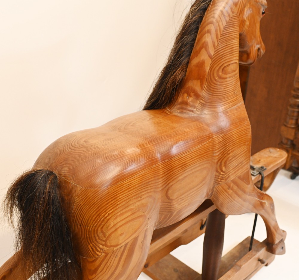 A hand-carved wooden rocking horse on a stationary wooden glider stand featuring a dark horsehair mane and tail. View VI