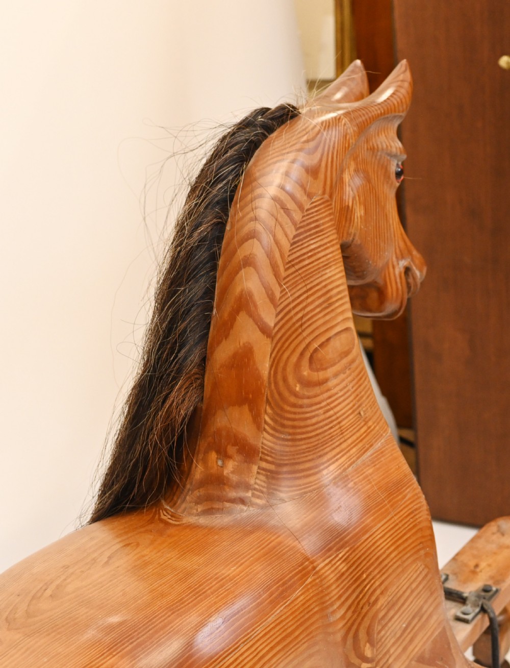A hand-carved wooden rocking horse on a stationary wooden glider stand featuring a dark horsehair mane and tail. View VII