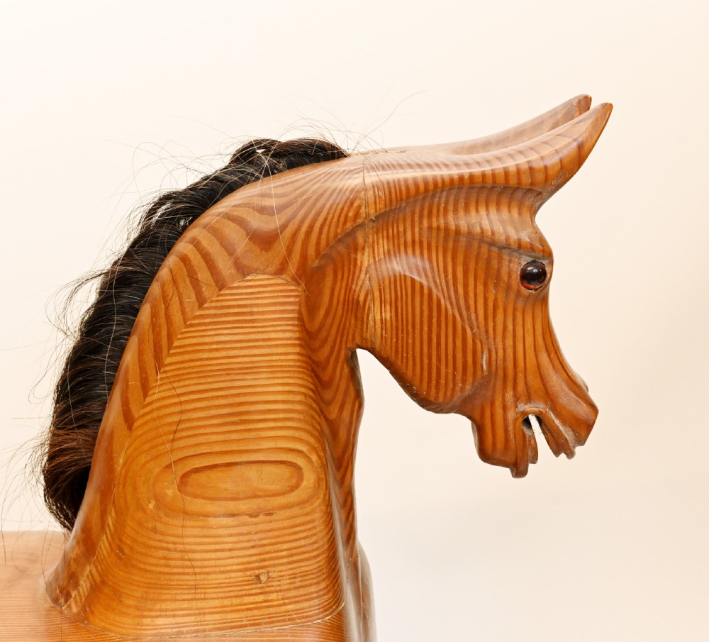 A hand-carved wooden rocking horse on a stationary wooden glider stand featuring a dark horsehair mane and tail. View VIII