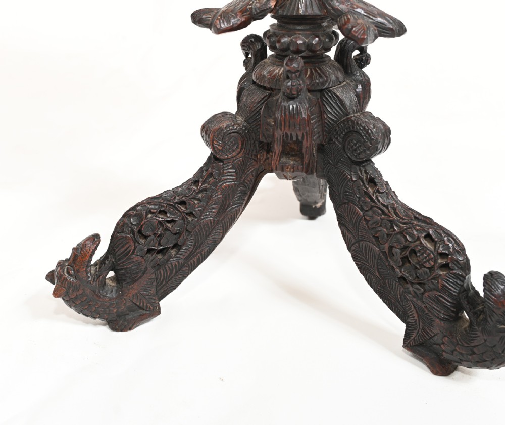 A circular 19th-century Burmese carved teak side table featuring intricate relief borders, a central plain top, a carved twisted stem, and tripod zoomorphic feet. View IV