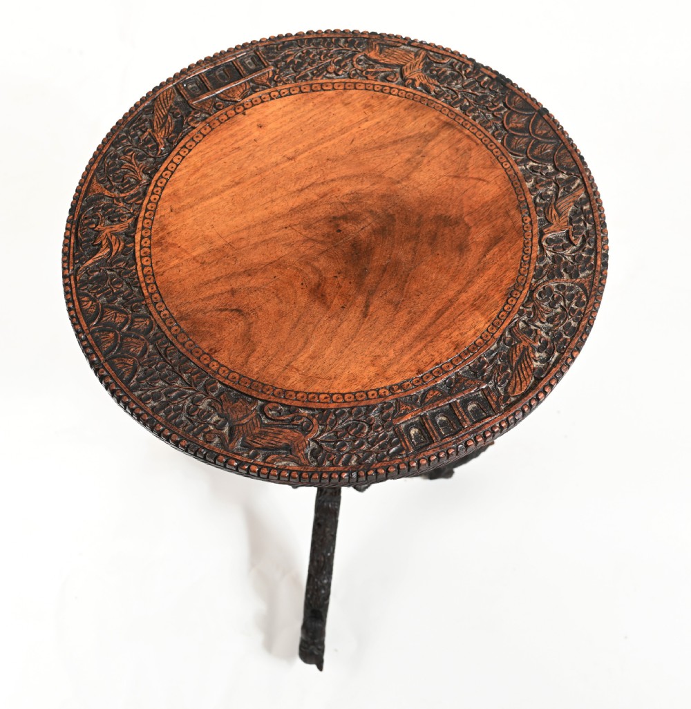A circular 19th-century Burmese carved teak side table featuring intricate relief borders, a central plain top, a carved twisted stem, and tripod zoomorphic feet. View V